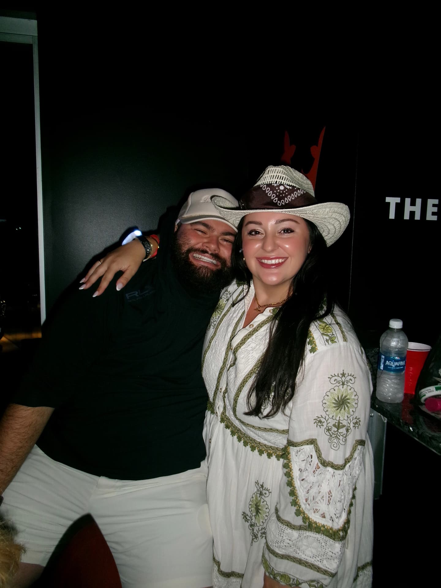 Jaime and Nolan laughing in cowboy hats at a party
