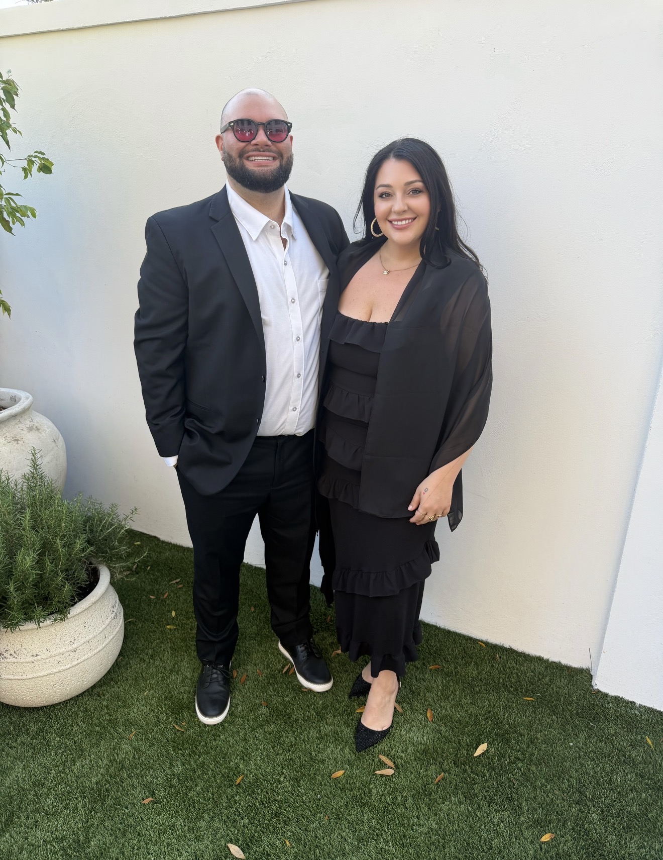 Jaime and Nolan dressed in black for a wedding in a sunny courtyard